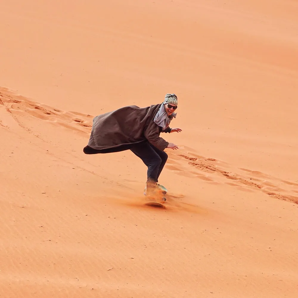 young-man-smiling-sand-dune-surfing-wearing-bisht-traditional-bedouin-coat-sandsurfing-is-one-attractions-wadi-rum-desert_692357-6845-min اسکی روی شن در سافاری دبی
