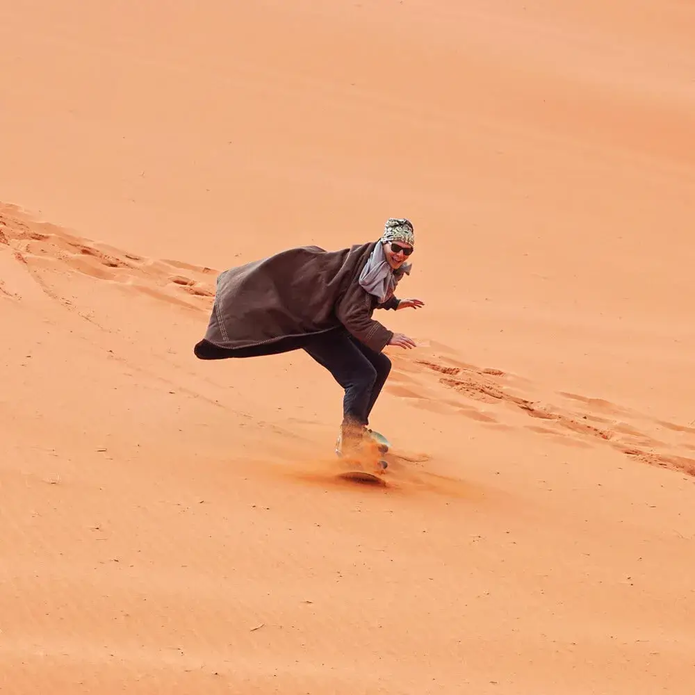 young-man-smiling-sand-dune-surfing-wearing-bisht-traditional-bedouin-coat-sandsurfing-is-one-attractions-wadi-rum-desert_692357-6845-min (1) اسکی روی شن در سافاری دبی